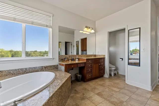 a spacious bathroom with a tub sink and mirror