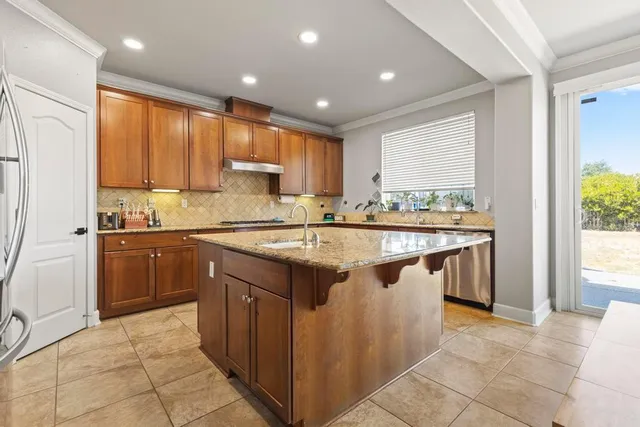 a kitchen with kitchen island granite countertop a sink stove and refrigerator