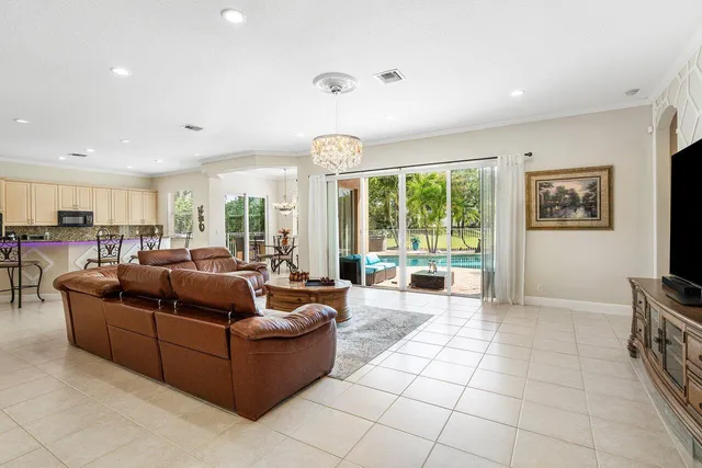 a kitchen with stainless steel appliances kitchen island granite countertop a stove a sink a refrigerator with white cabinets and couches