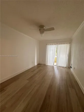 a view of an empty room with wooden floor and window