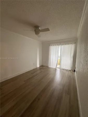 a view of an empty room with wooden floor and window