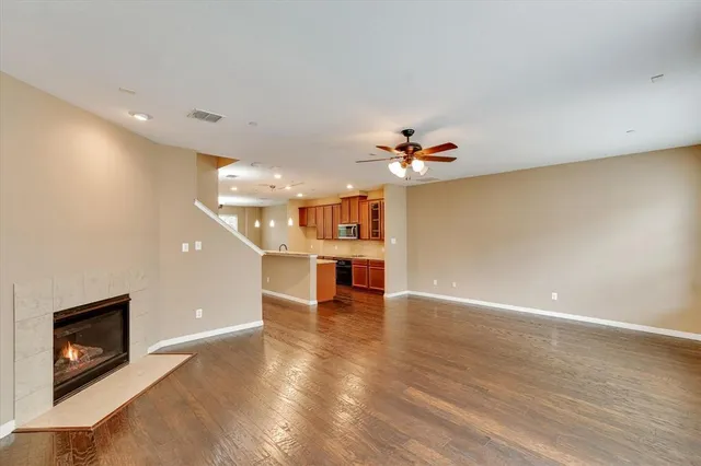 a view of an empty room with wooden floor and a fireplace
