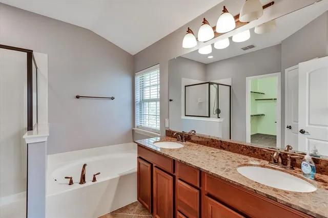 a bathroom with a granite countertop sink a large mirror and a bathtub