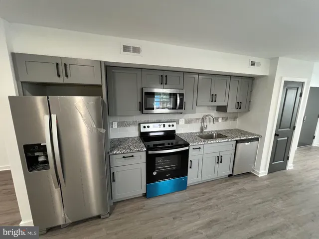 a kitchen with stainless steel appliances granite countertop a refrigerator stove and sink