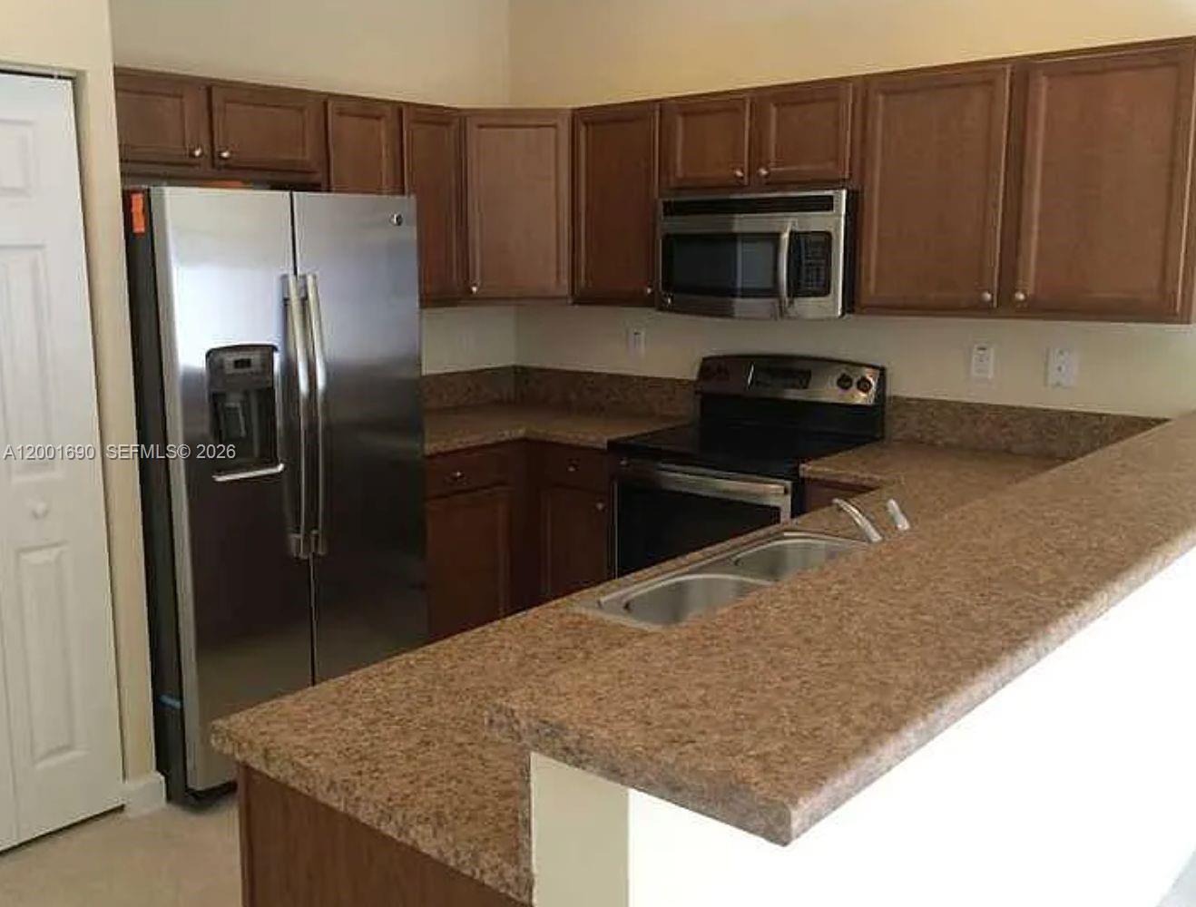 8913 West 35th Way Hialeah, FL 33018 - Photo 4 of 7 a kitchen with granite countertop a refrigerator and a stove top oven