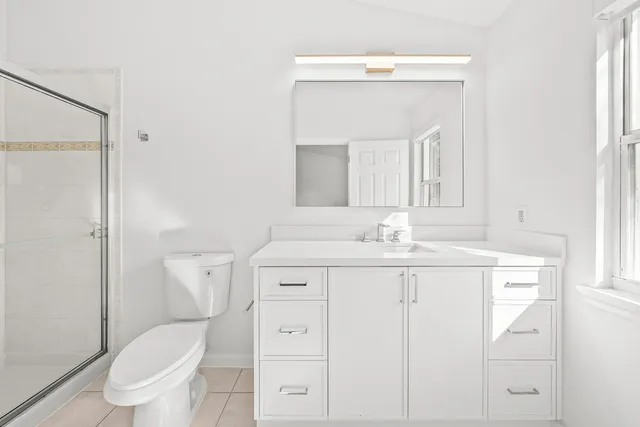 a bathroom with a granite countertop sink a toilet and shower