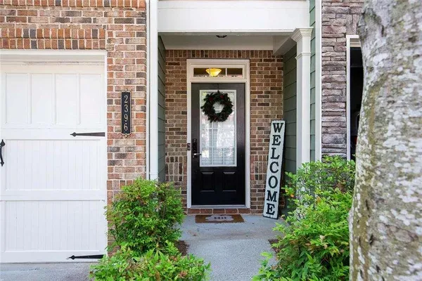 a view of a door of the house with potted plants