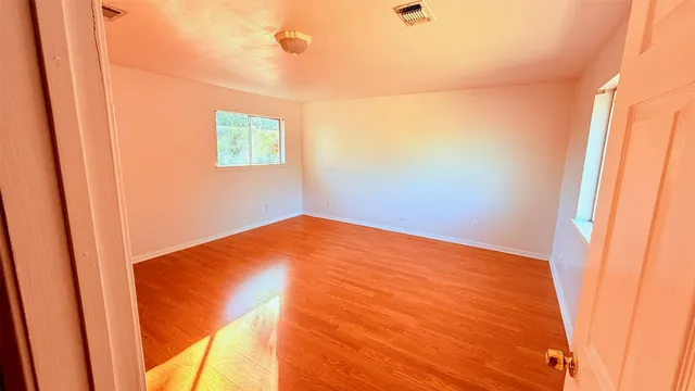 a view of a big room with wooden floor and a window