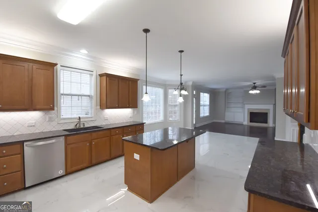 a kitchen with stainless steel appliances granite countertop a stove a sink a refrigerator and couches