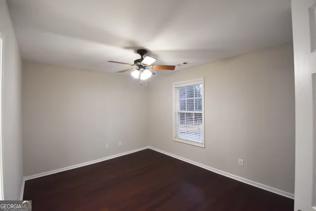 an empty room with wooden floor and ceiling fan