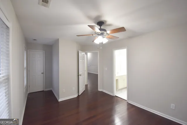 an empty room with wooden floor chandelier and windows