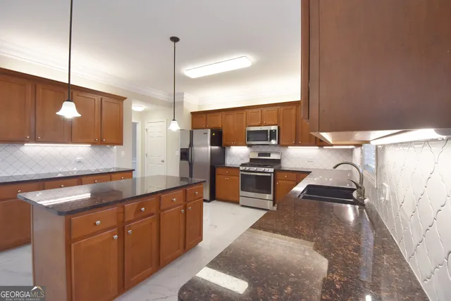 a kitchen with stainless steel appliances granite countertop a sink a stove and a refrigerator