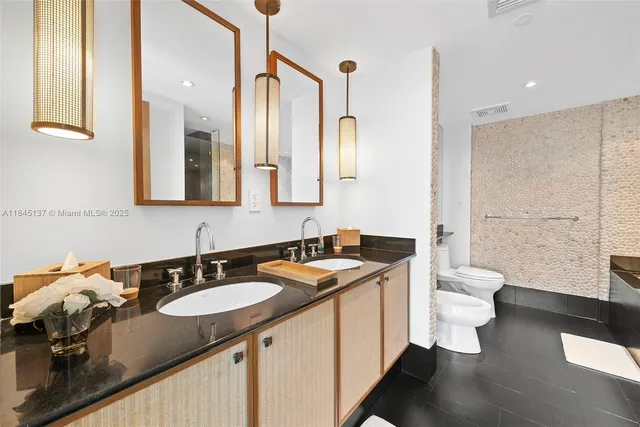 a bathroom with a granite countertop sink a toilet a mirror and shower