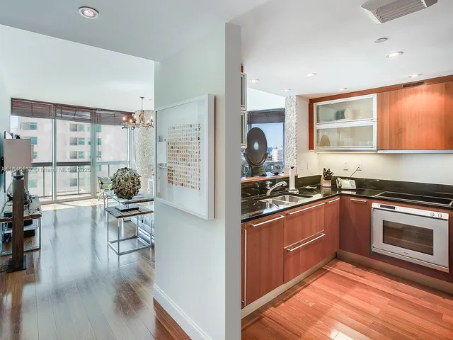 a kitchen with stainless steel appliances granite countertop a stove top oven a sink dishwasher and cabinets with wooden floor