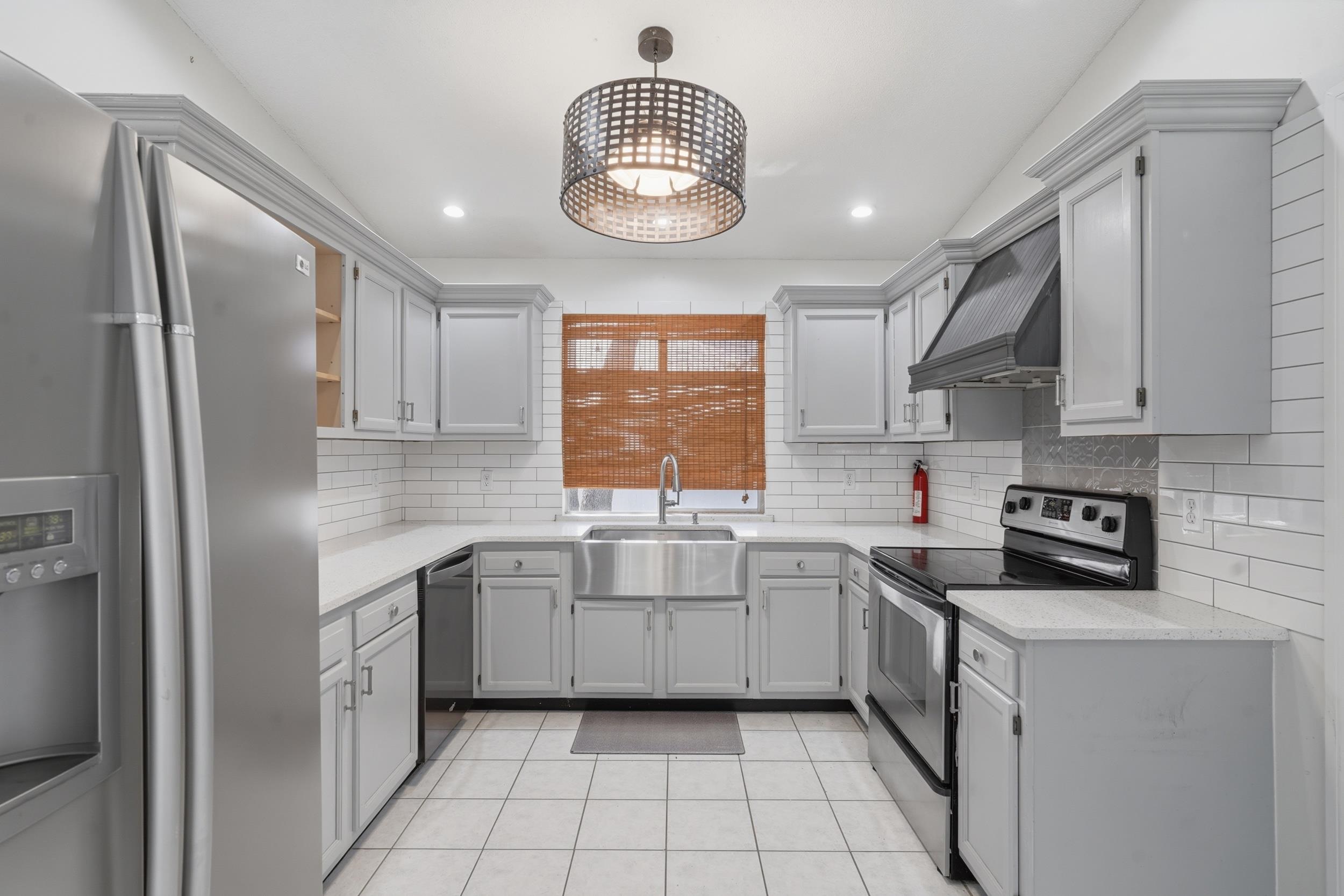 904 Alicante Road St. Augustine, FL 32086 - Photo 11 of 32 Kitchen with gray cabinetry, stainless steel appliances, light tile patterned flooring, light stone countertops, and decorative backsplash