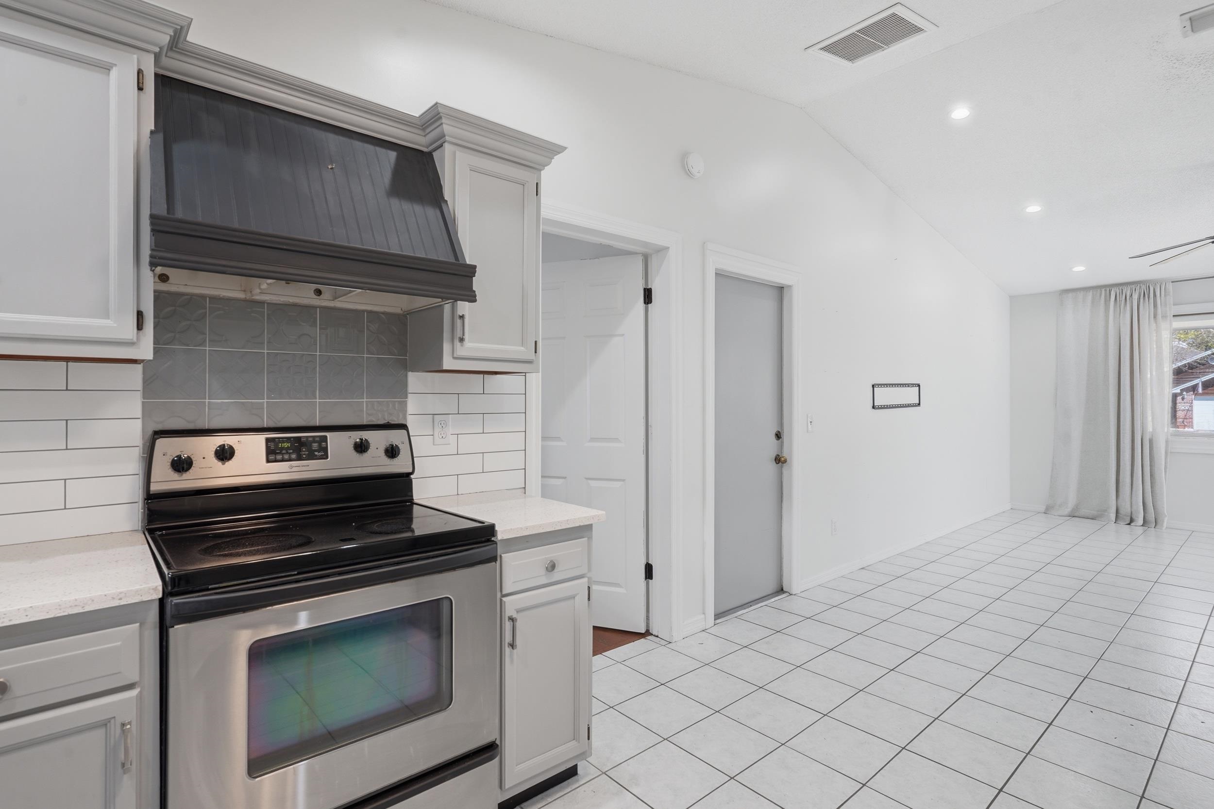 904 Alicante Road St. Augustine, FL 32086 - Photo 13 of 32 Kitchen featuring electric range, lofted ceiling, decorative backsplash, light tile patterned floors, and white cabinets