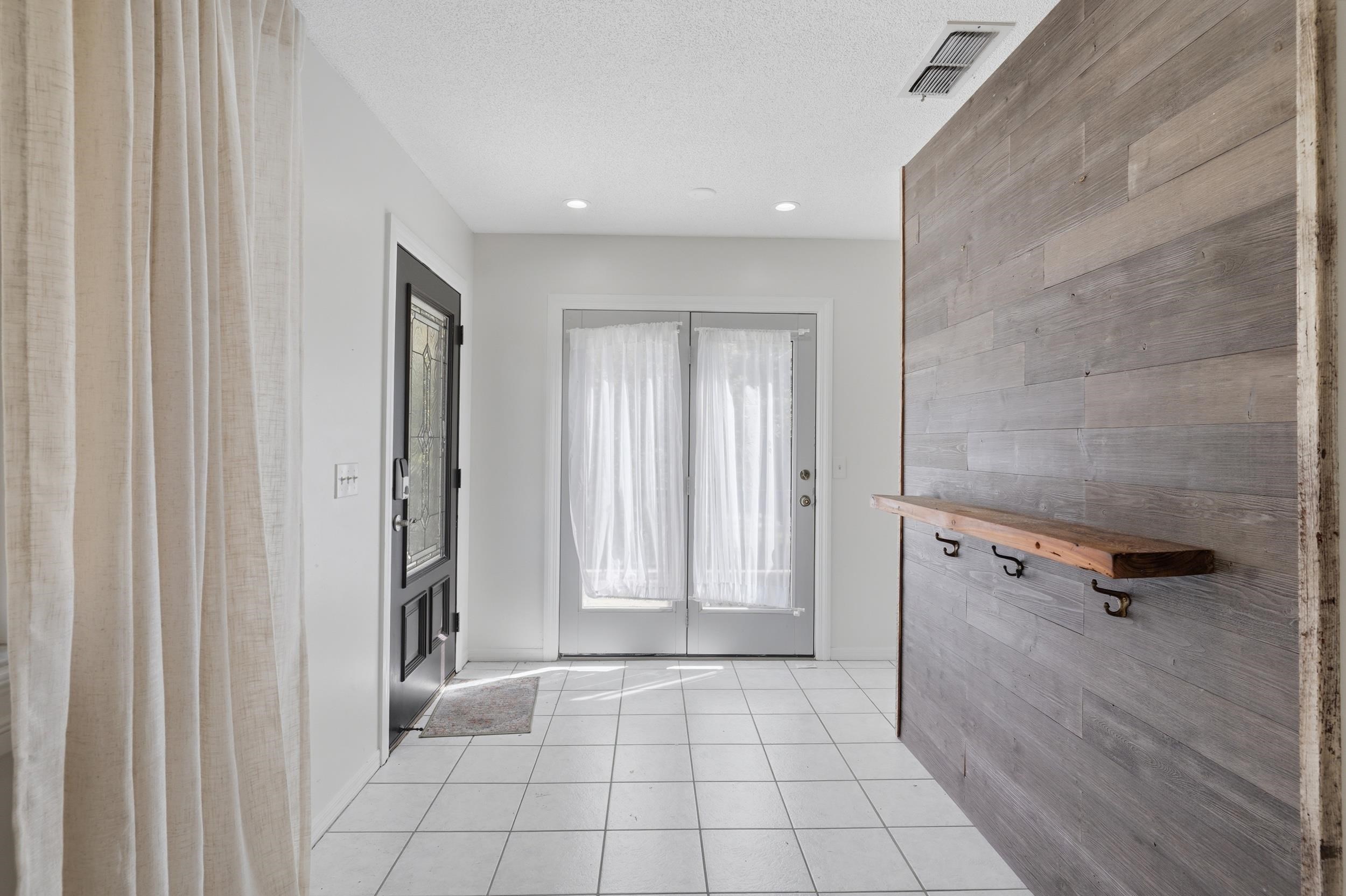 904 Alicante Road St. Augustine, FL 32086 - Photo 6 of 32 Foyer entrance featuring wood walls, light tile patterned flooring, a textured ceiling, an accent wall, and recessed lighting