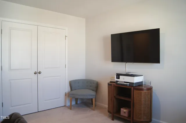 a bedroom with a bed and a flat tv screen on dresser
