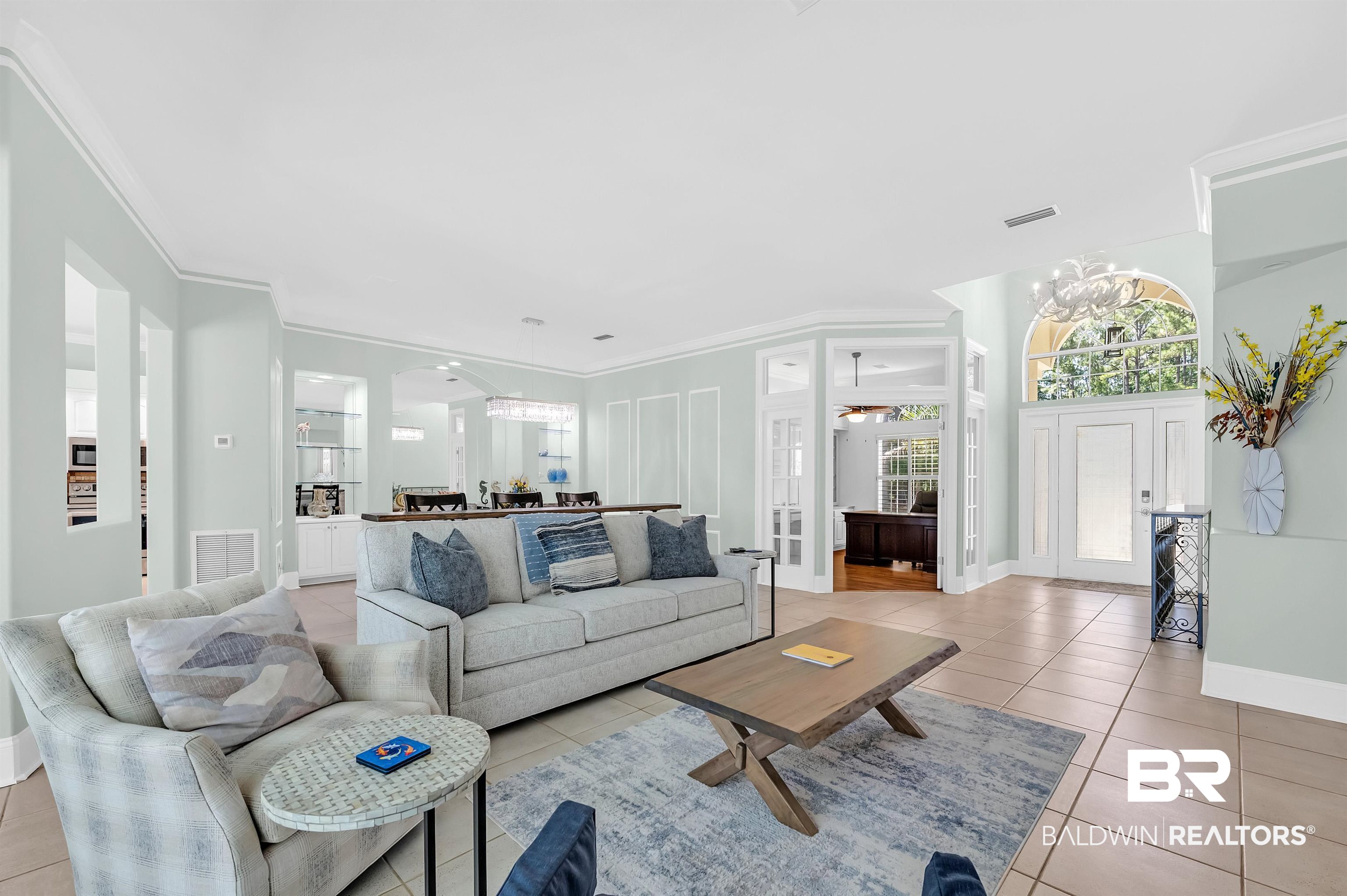8160 Bay View Drive Foley, AL 36535 - Photo 13 of 43 Living area with light tile patterned floors, ornamental molding, baseboards, arched walkways, and a chandelier