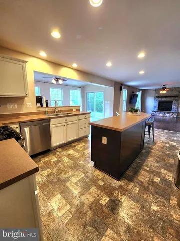 a view of a kitchen with kitchen island a sink wooden floor and counter top space