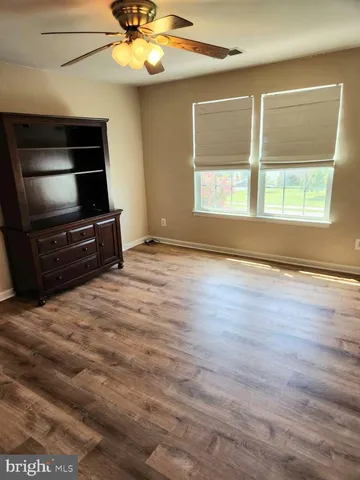 a view of room with hardwood floor and a ceiling fan