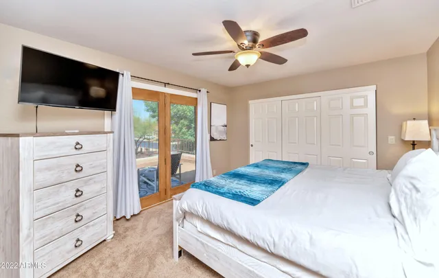 a bedroom with a large bed and a flat tv screen on dresser