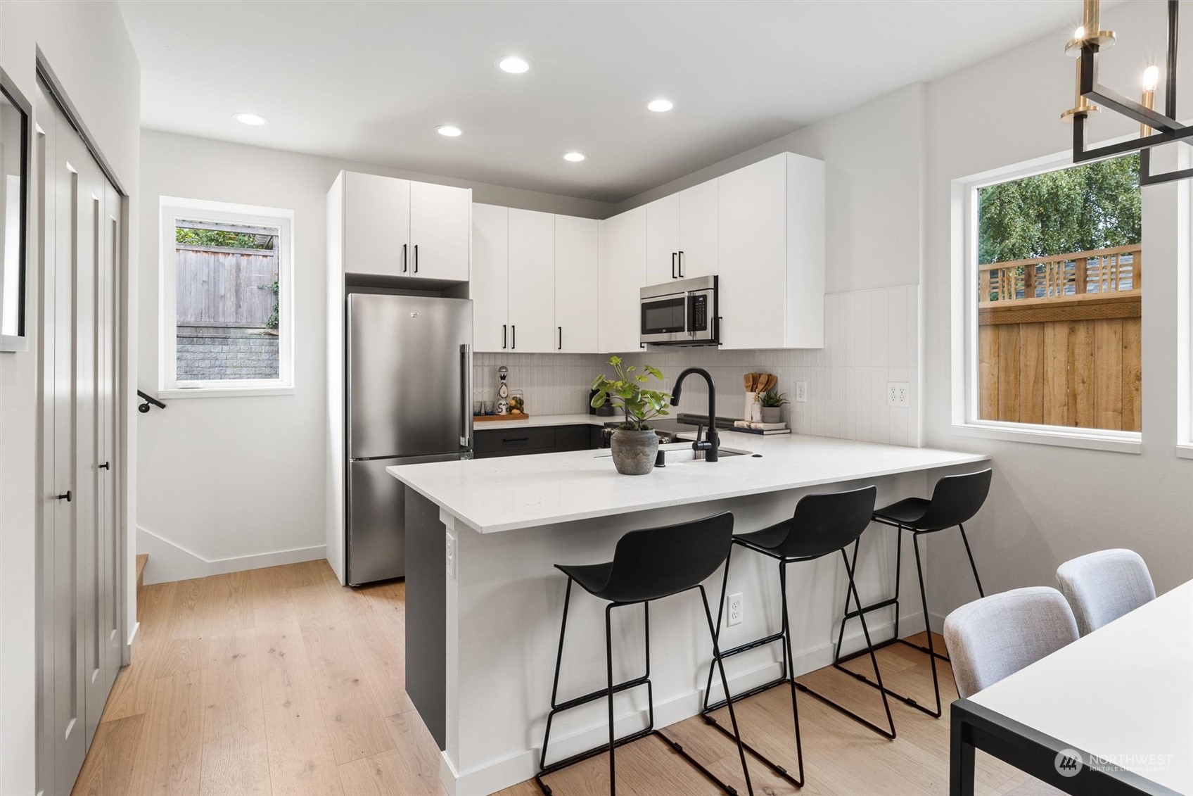 8021 17th Avenue Northwest Seattle, WA 98117 - Photo 11 of 23 a kitchen with stainless steel appliances a dining table chairs refrigerator and microwave