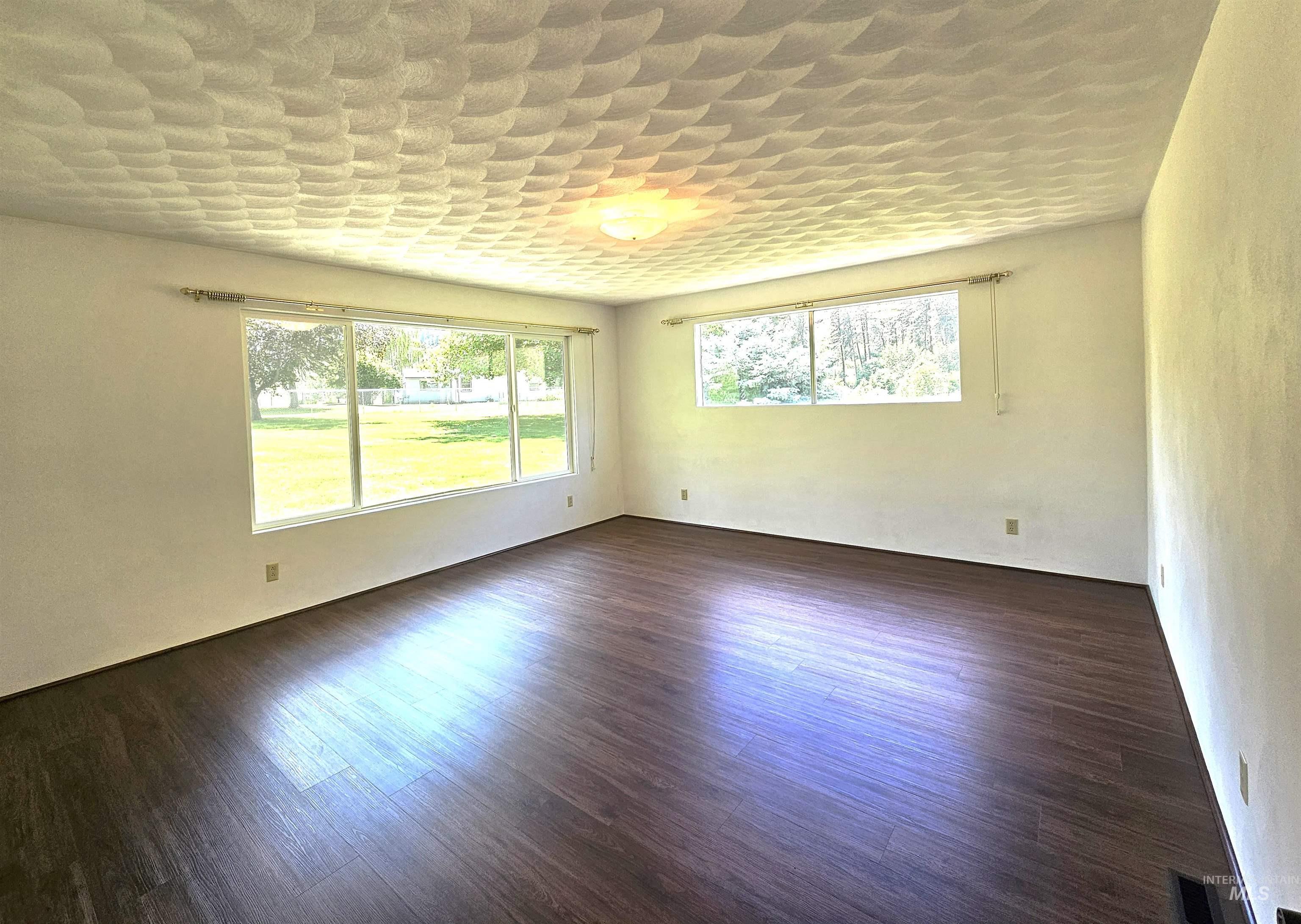 29865 Mission Creek Road Culdesac, ID 83524 - Photo 28 of 43 Spacious room featuring wood-finish flooring, a decorative ceiling fixture, white walls, and multiple large windows offering abundant natural light and exterior views