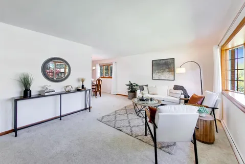 a living room with furniture a clock on wall and a window