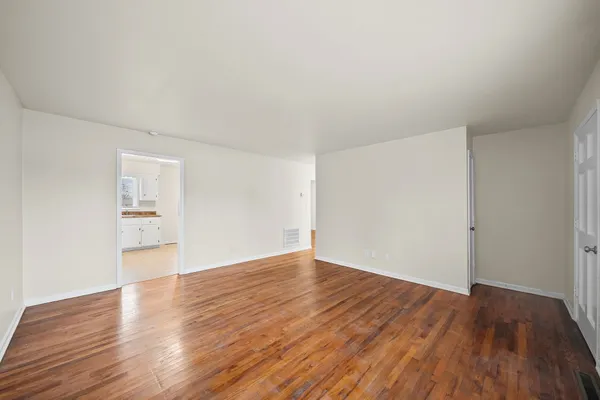 a view of an empty room with wooden floor and a window