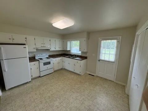a kitchen with granite countertop white cabinets and white appliances