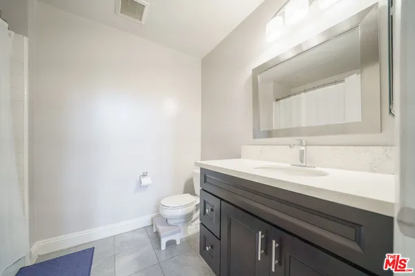 a bathroom with a granite countertop sink a toilet and a mirror