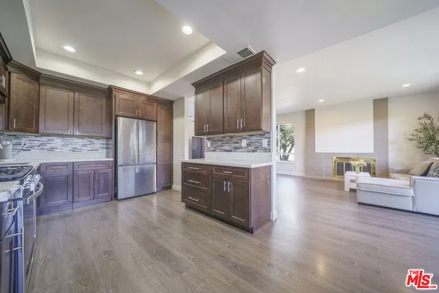 a kitchen with stainless steel appliances a refrigerator a stove a sink cabinets and wooden floor