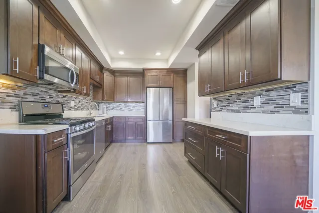 a kitchen with stainless steel appliances granite countertop wooden cabinets a sink and dishwasher a stove top oven with wooden floor