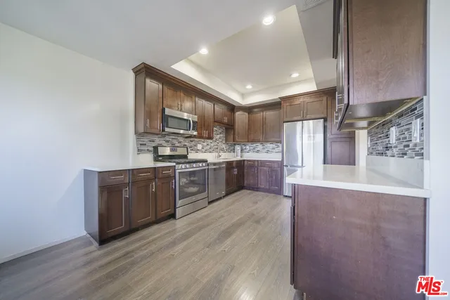a large kitchen with stainless steel appliances granite countertop a stove a sink dishwasher and a oven with wooden floors