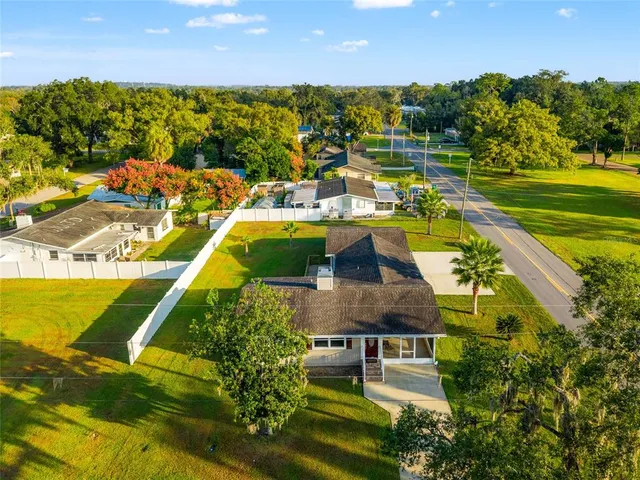 a view of a swimming pool with a lawn chairs under an umbrella and yard