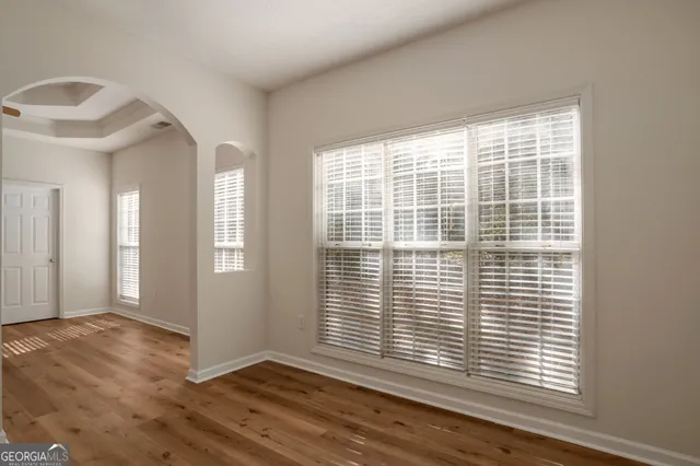 a view of an empty room with wooden floor and a window