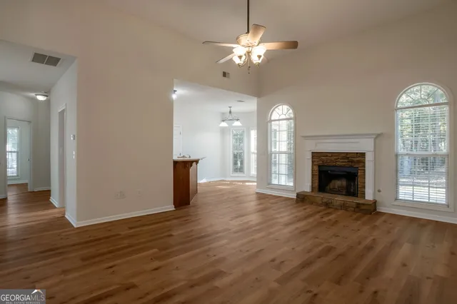 a view of an empty room with wooden floor fireplace and a window