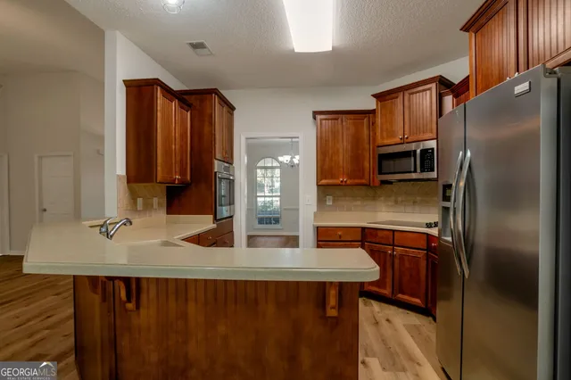 a kitchen with stainless steel appliances granite countertop a refrigerator a stove and a sink with wooden floor