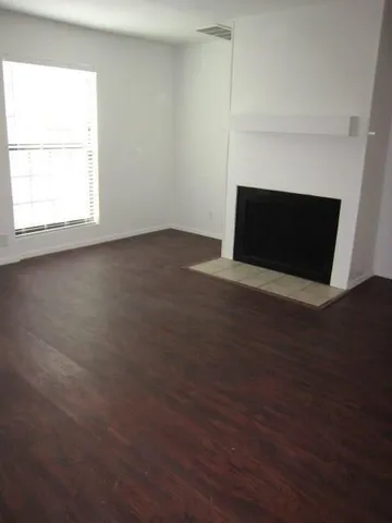 an empty room with wooden floor and fireplace