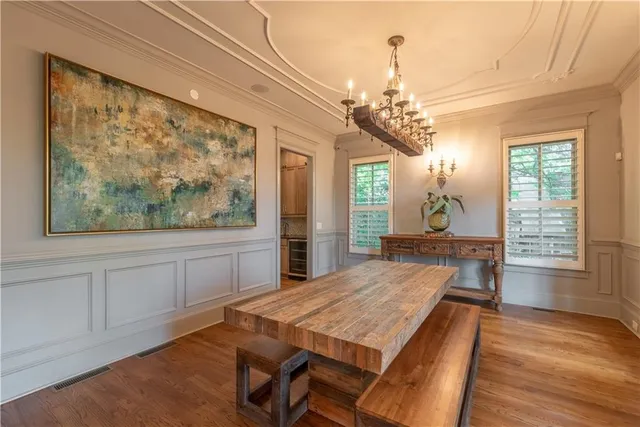 a dining room with wooden floor a chandelier a wooden table and chairs