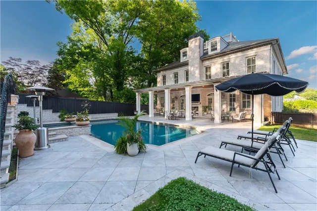 a view of a patio with a table and chairs under an umbrella with potted plants and trees