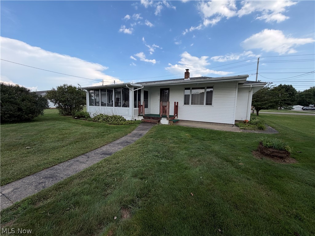 6063 East State Road Newcomerstown, OH 43832 - Photo 24 of 31 White siding exterior with a screened-in porch, front entry porch, mature landscaping, and a concrete pathway