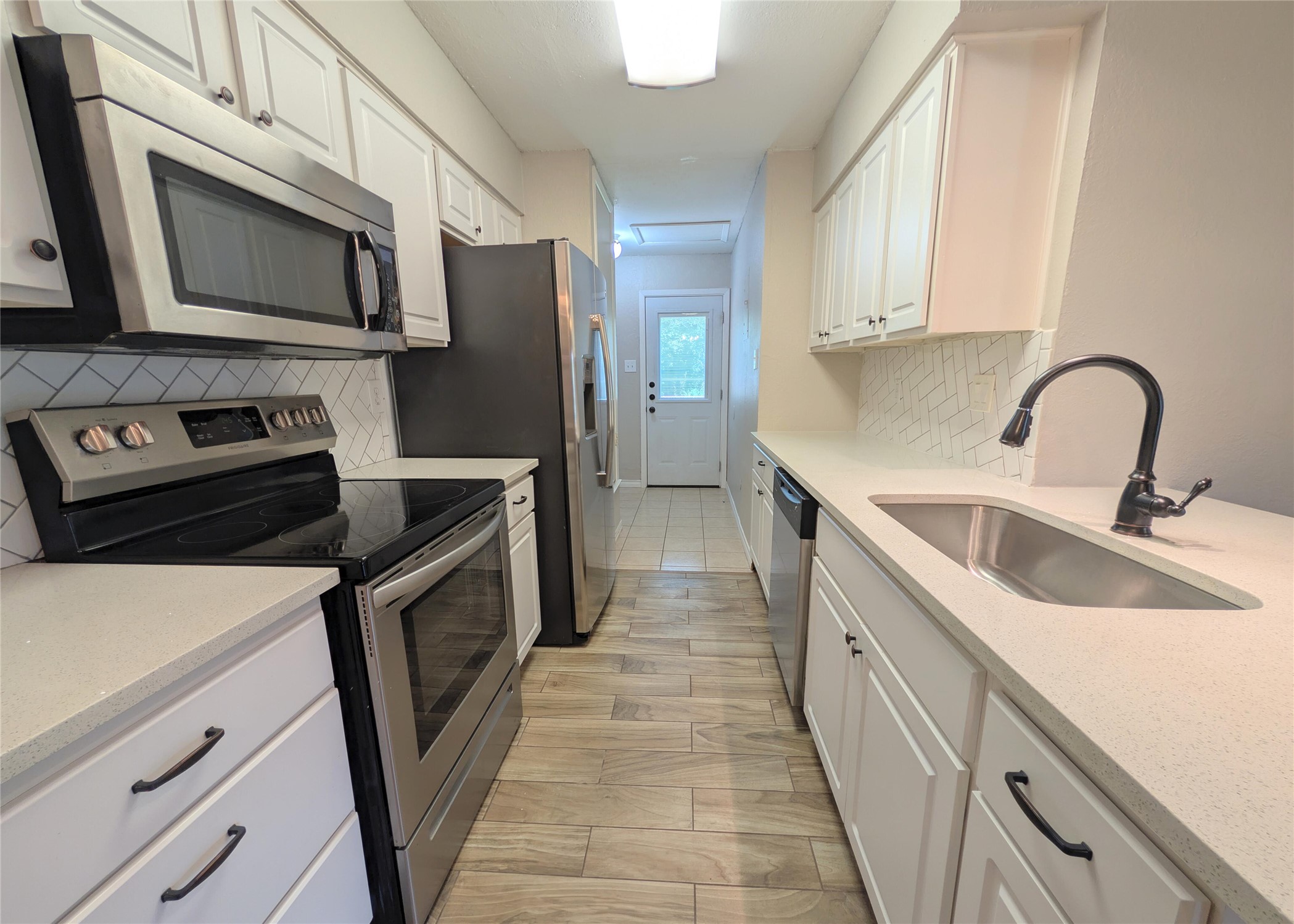 12601 Turtle Rock Road, Unit B Austin, TX 78729 - Photo 4 of 20 Stainless Steel appliances and large sink. Quartz countertops and tile backsplash and floor. Lots of cabinet space. Laundry and back door through kitchen.