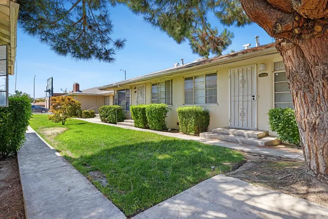 a view of a house with a yard and potted plants
