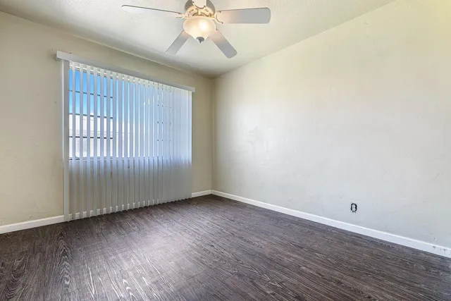 an empty room with wooden floor and ceiling fan