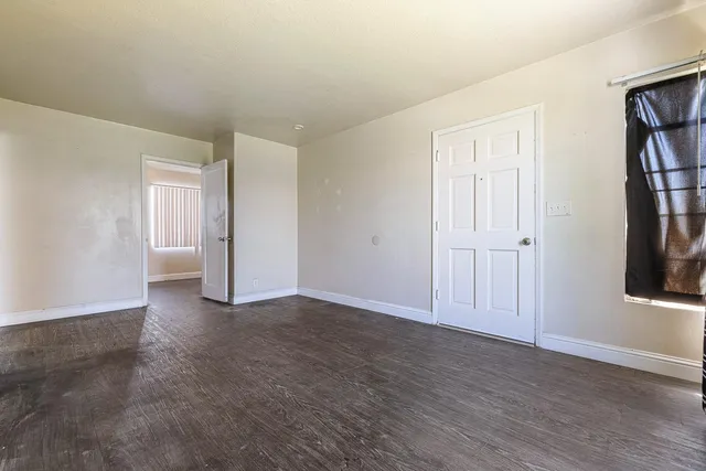 a view of an empty room with wooden floor and windows
