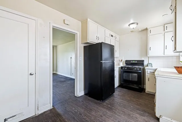 a kitchen with white cabinets and wooden floor