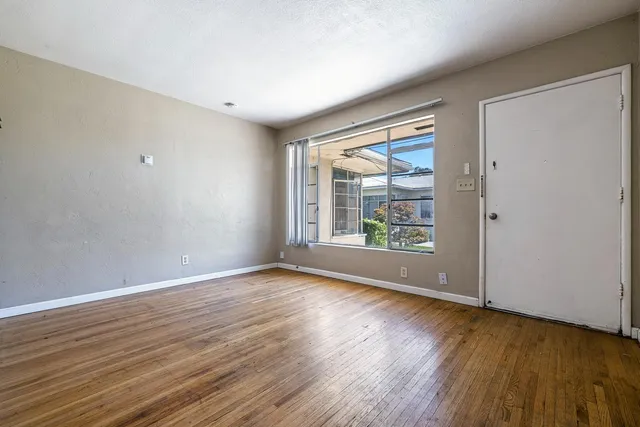 a view of an empty room with window and wooden floor