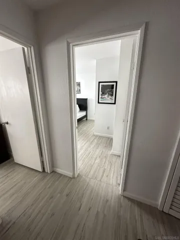 a view of a hallway with wooden floor and a cabinet